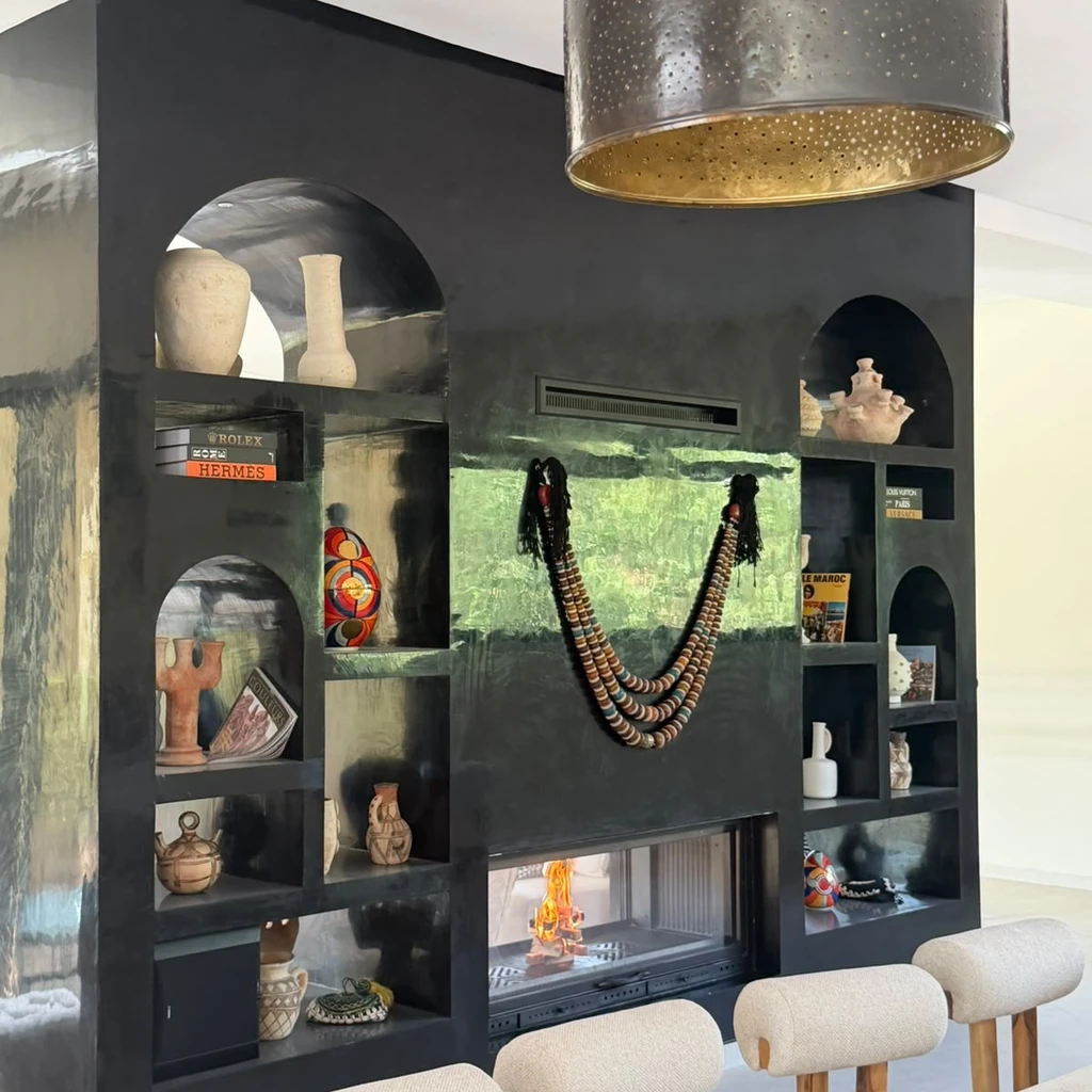 Cheminée vitrée intégrée dans un meuble bibliothèque noir avec niches décoratives.